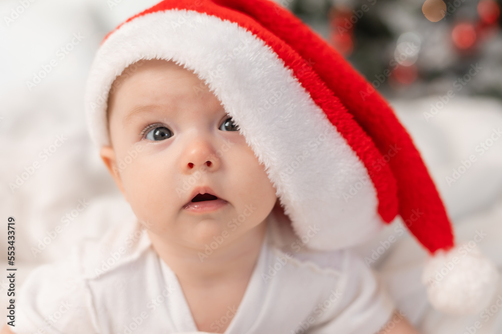 cute baby in Santa hat at home in bed. The first New Year. Christmas Gift cute baby in Santa hat at home in bed. The first New Year. Christmas Gift