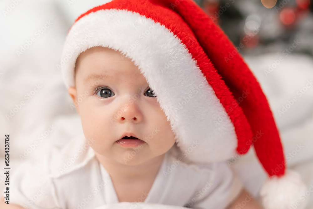 cute baby in Santa hat at home in bed. The first New Year. Christmas Gift cute baby in Santa hat at home in bed. The first New Year. Christmas Gift