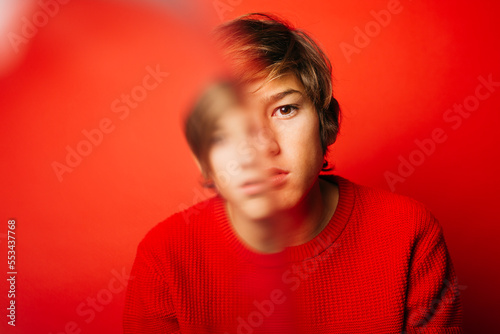 Studio portrait of a thoughtful, blury pre-adolescent boy over a red background