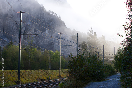 Scenic landscape at Anterior Rhine Valley with cliff, gorge, railway track and woodland on a blue foggy autumn morning. Photo taken September 26th, 2022, Versam, Switzerland.