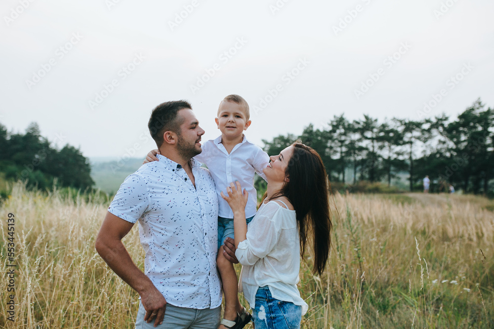 Happy young family father, mother and little son having fun outdoors, playing together in park Happy young family father, mother and little son having fun outdoors, playing together in park