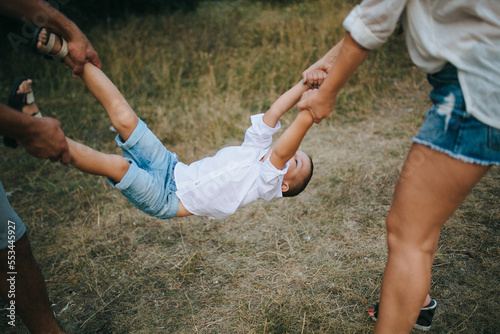 Happy young family father, mother and little son having fun outdoors, playing together in park