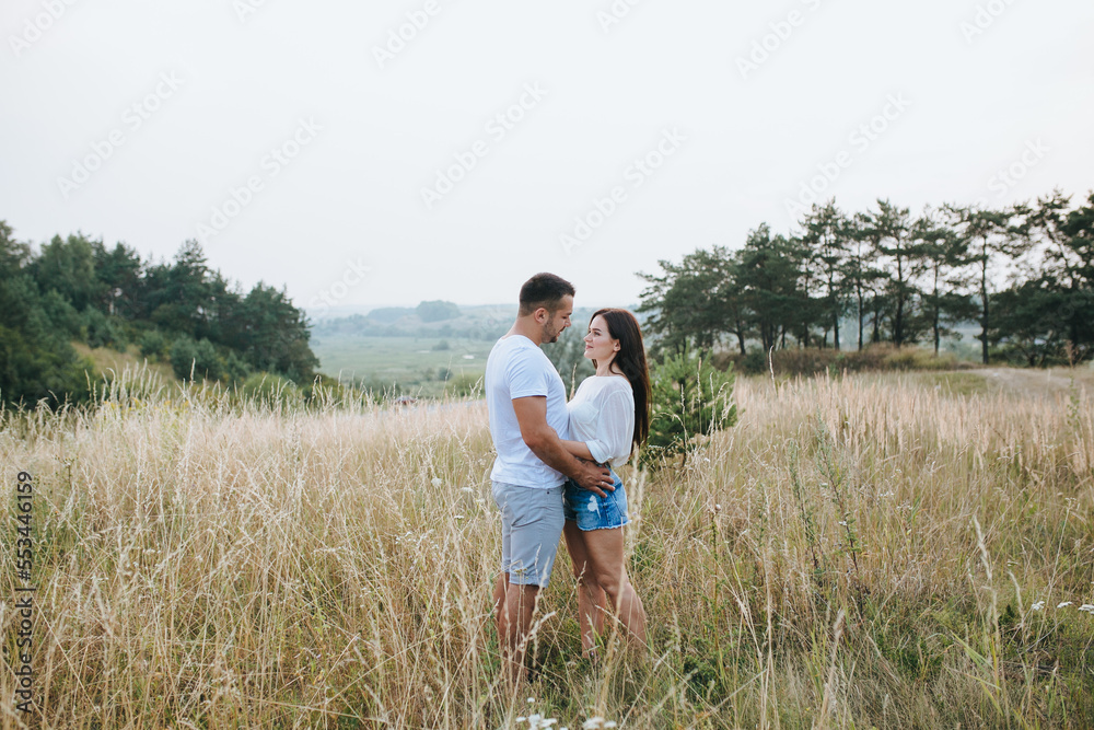 Happy in love romantic young cheerful couple man and woman walk together among the summer forest