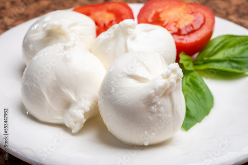 Eating of fresh handmade soft Italian cheese from Puglia, white balls of burrata or burratina cheese made from mozzarella and cream filling