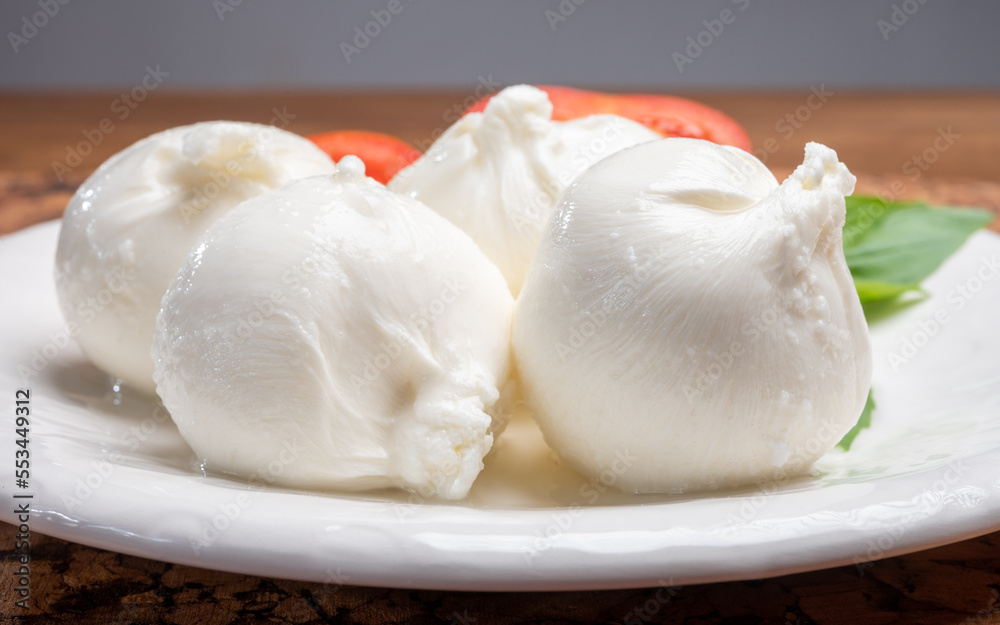 Eating of fresh handmade soft Italian cheese from Puglia, white balls of burrata or burratina cheese made from mozzarella and cream filling Eating of fresh handmade soft Italian cheese from Puglia, white balls of burrata or burratina cheese made from mozzarella and cream filling