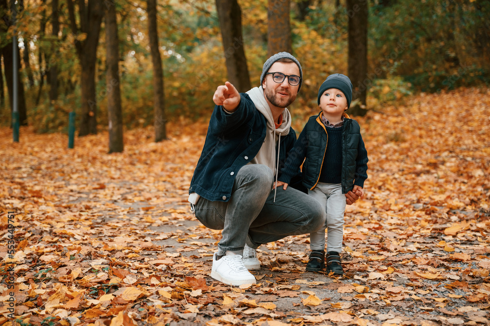 In the autumn forest. Father and young son is together outdoors at daytime In the autumn forest. Father and young son is together outdoors at daytime
