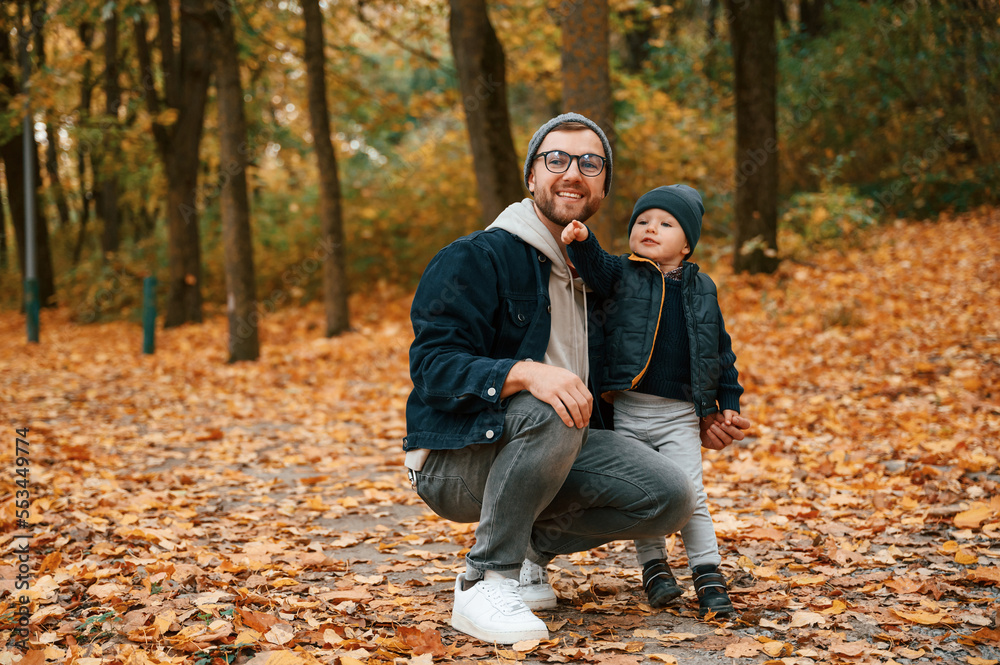 In the autumn forest. Father and young son is together outdoors at daytime In the autumn forest. Father and young son is together outdoors at daytime