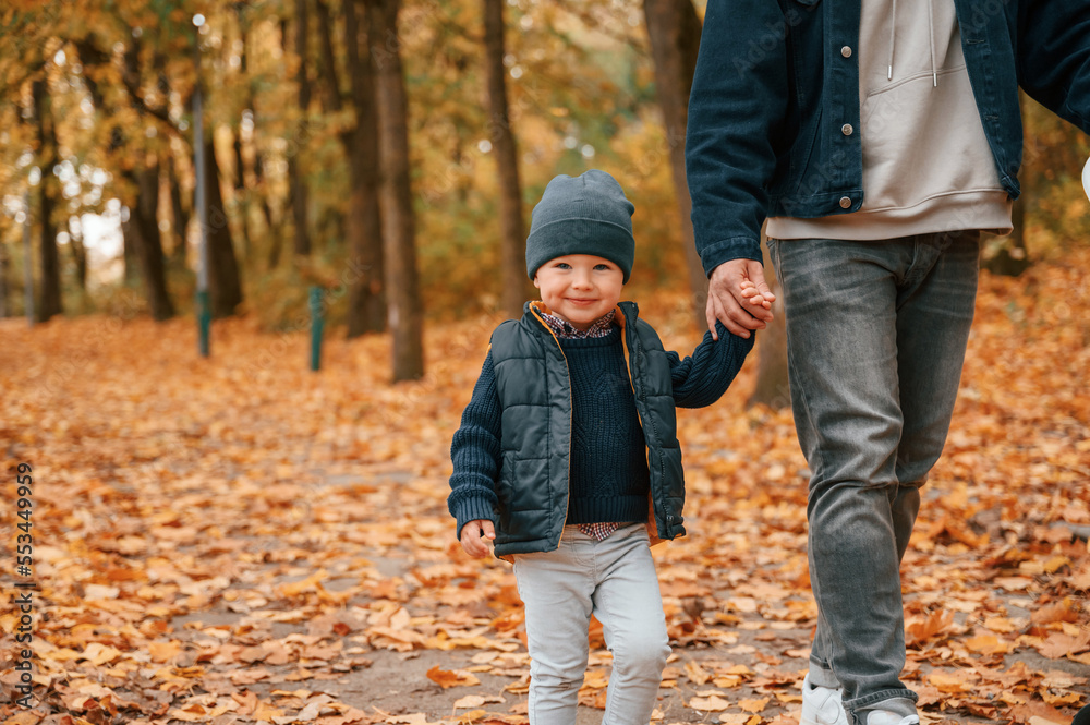 Holding hands. Father and young son is together outdoors at daytime Holding hands. Father and young son is together outdoors at daytime