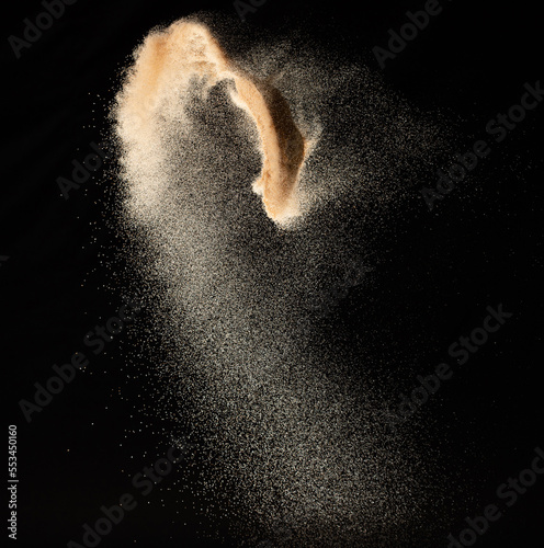 Small size fine Sand flying explosion, Golden grain wave explode. Abstract cloud fly. Yellow colored sand splash silica in Air. Black background Isolated high speed shutter, throwing freeze shot