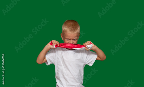 Embittered boy pulls paper with his hands, tries to tear it. Protest, fatigue, training, coercion, discontent, disobedience, upbringing, denial. Selective focus.