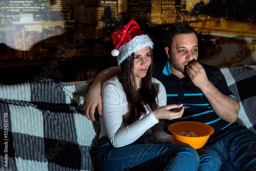 Woman and man are watching TV, eating popcorn. Selective focus. Picture for website about family, Christmas.