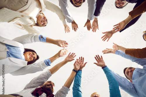 Team of business people celebrating teamwork. Group of happy people standing in circle, putting hands together and smiling. Teamwork, unity, partnership concept. Low angle bottom view, shot from below