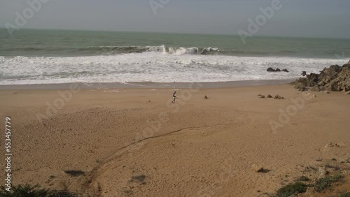 Chico corriendo por la playa en día encapotado photo