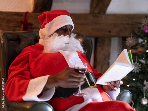 Santa Claus reading book and drinking wine in armchair?