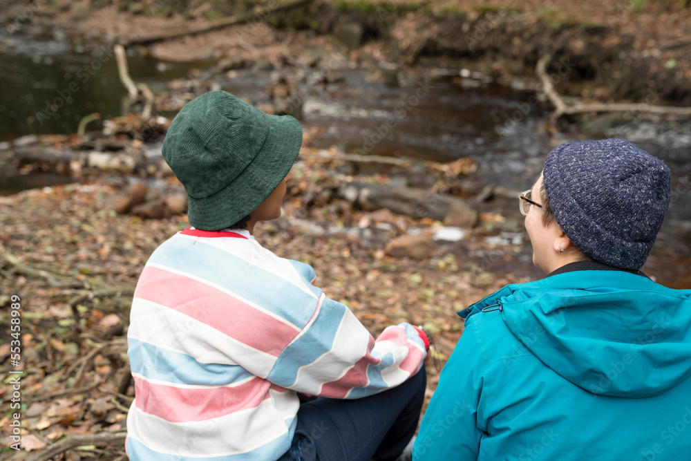 Female friends relaxing in forest by river Female friends relaxing in forest by river