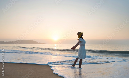 Happy woman standing on the beach with hands up.