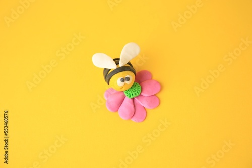 Bee with flower made from plasticine on orange background. Children's handmade ideas