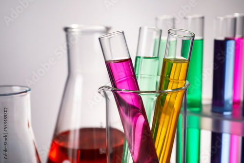 Different laboratory glassware with colorful liquids on grey background, closeup