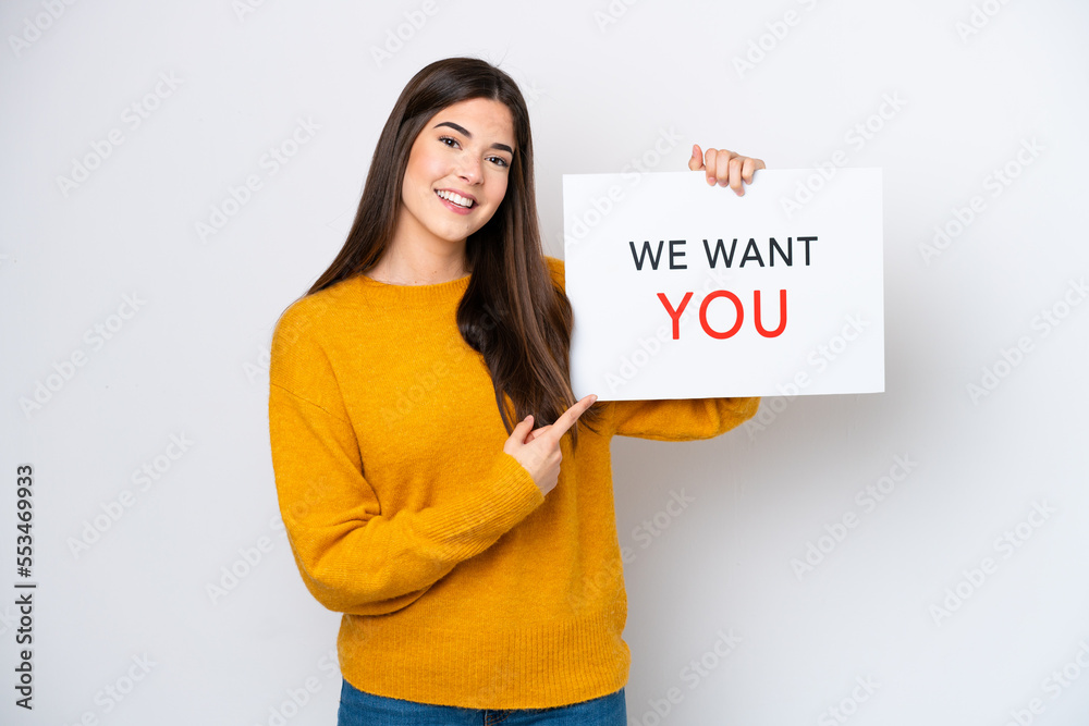 Young Brazilian woman isolated on white background holding We Want You board and pointing it Young Brazilian woman isolated on white background holding We Want You board and pointing it