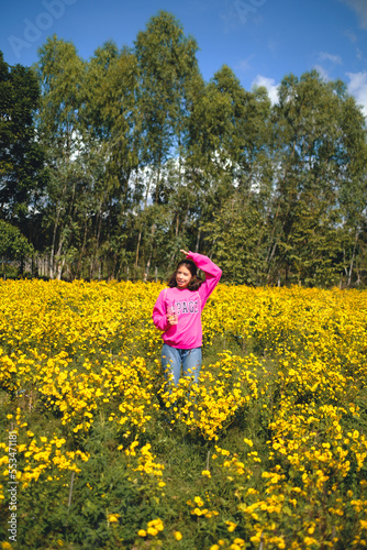 A woman wearing a pink dress is taking a walk in a yellow flower garden called Chrysanthemum during the day. At Pak Thong Chai District  Thailand 4-12-2022