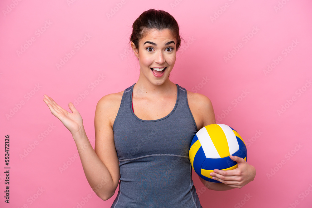 Young Brazilian woman playing volleyball isolated on pink background with shocked facial expression