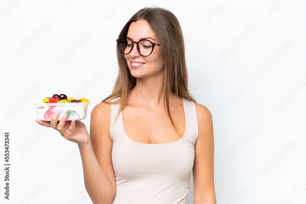 Young pretty woman holding a bowl of fruit isolated on white background with happy expression Young pretty woman holding a bowl of fruit isolated on white background with happy expression