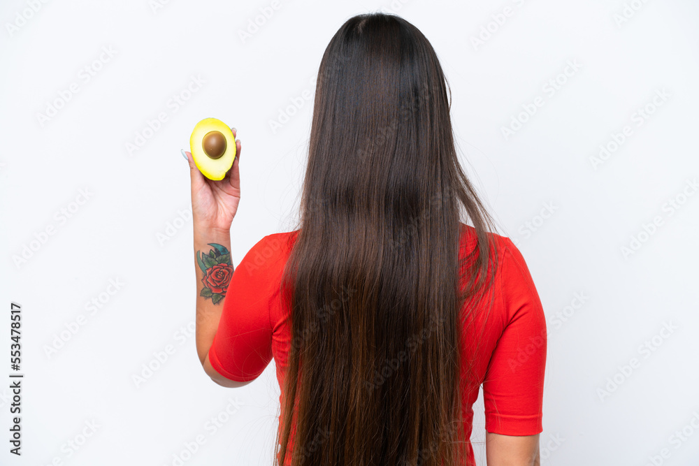 Young Asian woman holding an avocado isolated on white background in back position Young Asian woman holding an avocado isolated on white background in back position