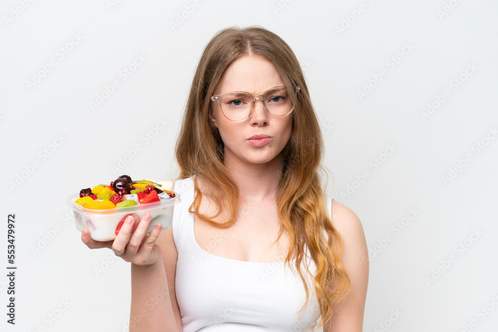 Young pretty woman holding a bowl of fruit isolated on white background with sad expression Young pretty woman holding a bowl of fruit isolated on white background with sad expression