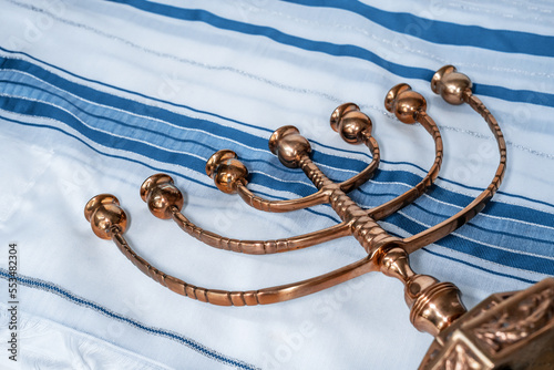 Large copper menorah lies on a blue-and-white folded tallit. Jewish traditions and religion (130) photo