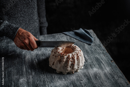 man cuts a gugelhupf cake with a kitchen knife photo
