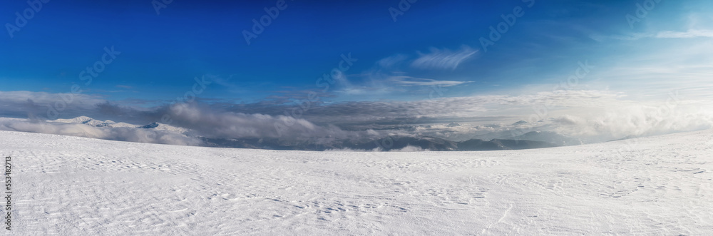 Clouds over a snow-covered mountain range. Winter mountain landscape.