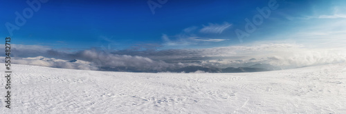 Clouds over a snow-covered mountain range. Winter mountain landscape.