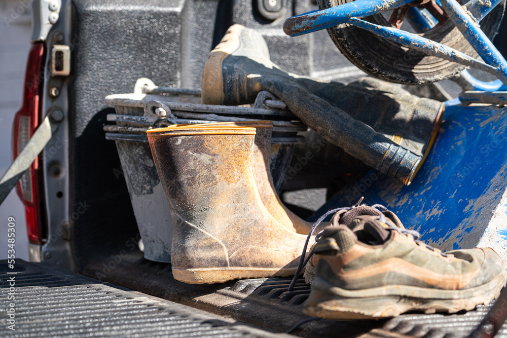 Dirty safety PPE and equipment of the construction worker which are placed on the truck of pick-up vehicle. Industrial working equipment object photo, selective focus.
