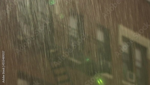 Night heavy rain and silhouette of many-storeyed house in the city. Rain is pouring heavily from the sky at the late evening. Night rain in the city