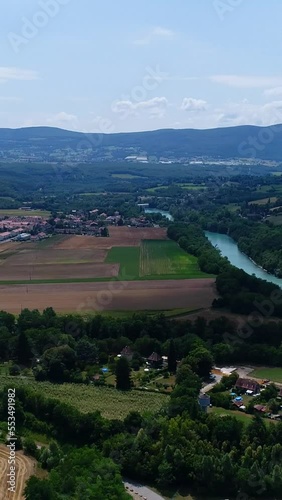 Vertical video of Aerial shot of fields and villages along a river, mountains in background photo