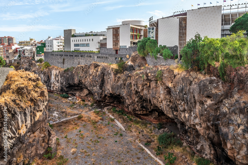 Canyon Barranco de Santos in Santa Cruz de Tenerife, Spain. Modern city buildings rise above the steep cliff of the volcanic gorge