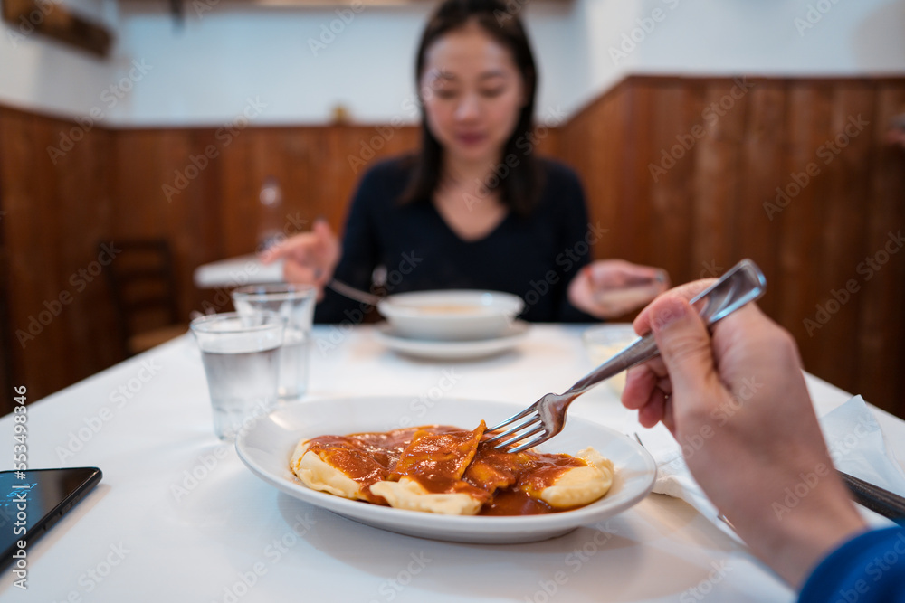 Young Asian lady eating soup during dinner with crop man Young Asian lady eating soup during dinner with crop man