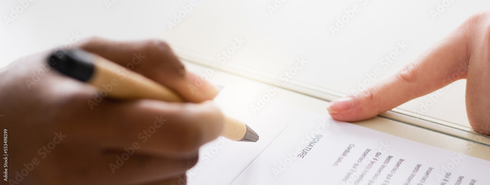 Close-up unrecognizable woman hand signing a contract. Horizontal banner or header. Agreement concept.