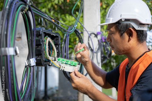 Obraz na plátně Technician standing on wooden ladder for inspection splitter box of fiber optic cable lines
