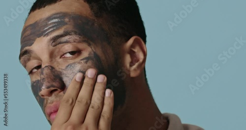Positive man face mask. Relaxed man making natural cosmetic facial procedure