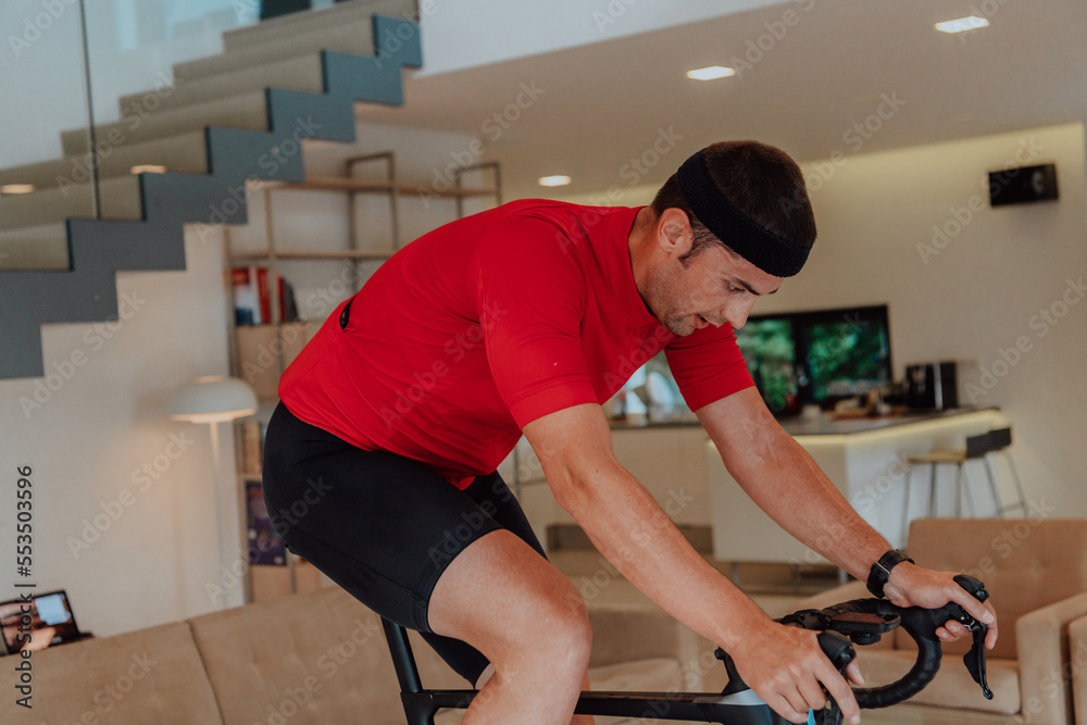 A man riding a triathlon bike on a machine simulation in a modern living room. Training during pandemic conditions.