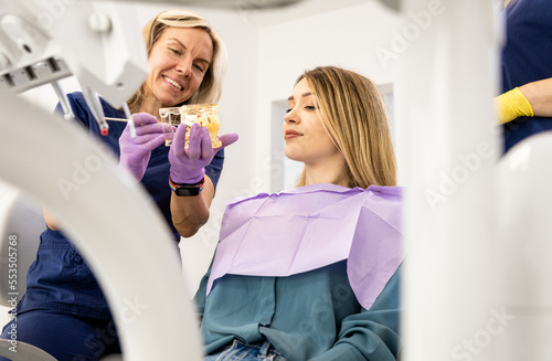 Female dentist takling with patient showing theet implant in dental clinic. photo