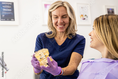 Female dentist takling with patient showing theet implant in dental clinic. photo