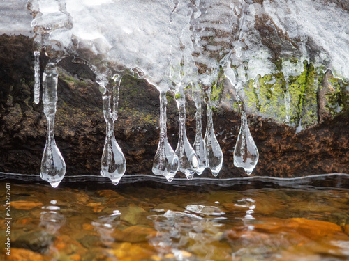 Transparent ice and ice icicles on stones on the shore of the Onega Lake in Karelia in autumn after frost photo