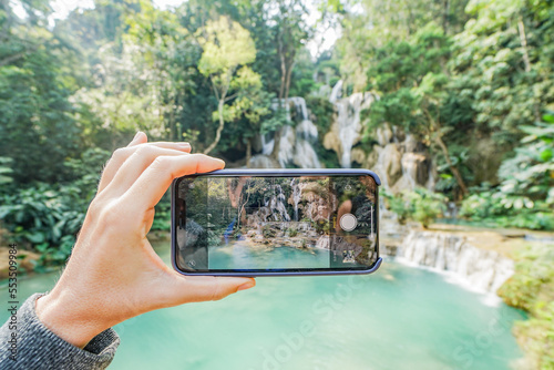 person taking a picture of a waterfall, mobilphone photo
