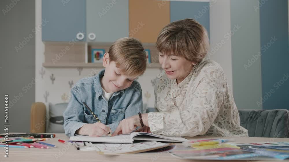 Grandma and grandson are doing homework. Portrait of a happy family. Learning at home. Teaching. Grandmother and grandson laugh. Cute emotions in the frame. The story of one family. Grandma and grandson are doing homework. Portrait of a happy family. Learning at home. Teaching. Grandmother and grandson laugh. Cute emotions in the frame. The story of one family.