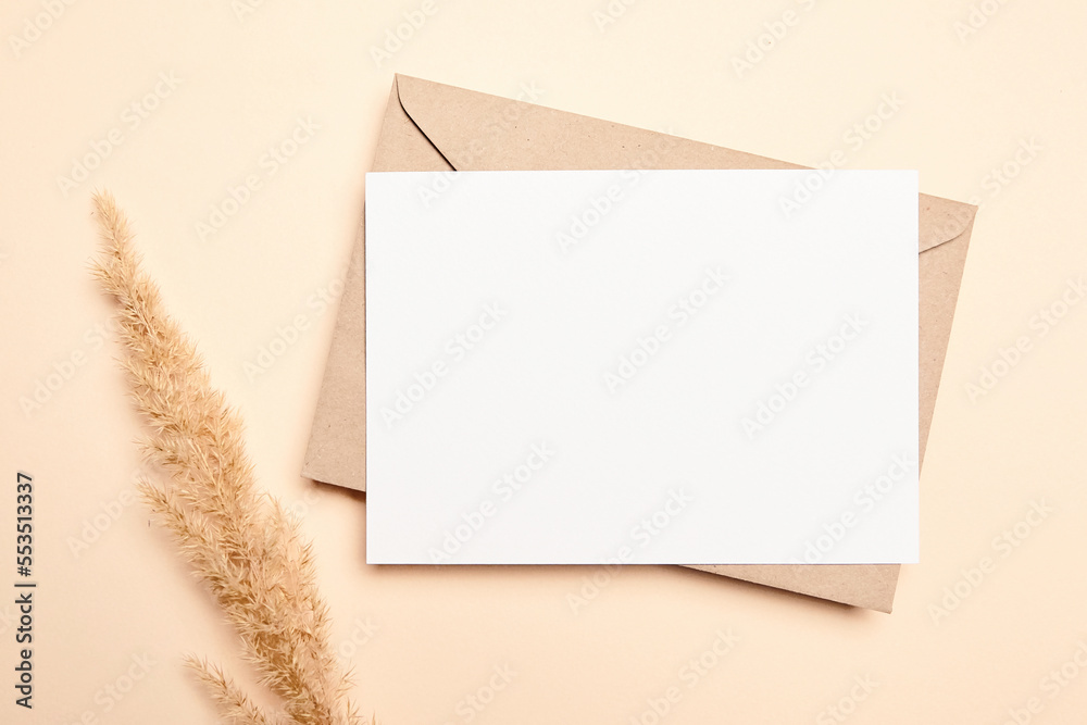 Holiday greeting card mockup with dry grass on beige background, top view, flat lay. White wedding invitation card Holiday greeting card mockup with dry grass on beige background, top view, flat lay. White wedding invitation card