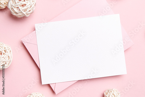 Holiday greeting card mockup with pink envelope and decoration on light pink background, top view, flat lay. Blank wedding invitation or Valentine Day letter, empty card © mikeosphoto