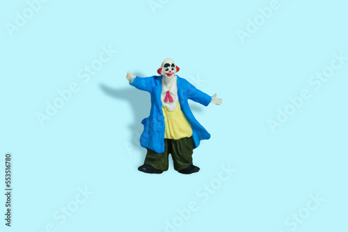 Miniature people toy figure photography. Full body of a bald clown with welcome pose. Isolate on blue background