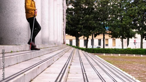 disabled person goes down the stairs orientating himself with the stick photo